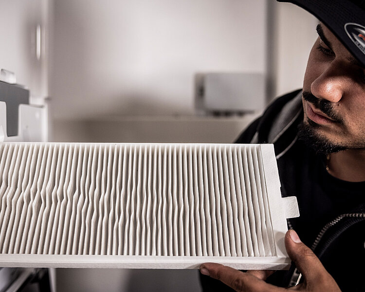Wartung eines Luftfilters durch Hackner-Fachkraft Mitarbeiter von Hackner Haustechnik prüft einen weißen Luftfilter an einem Lüftungsgerät